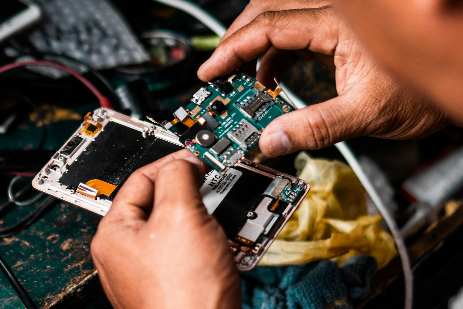 Technician opening a smartphone mainboard at a repair bench